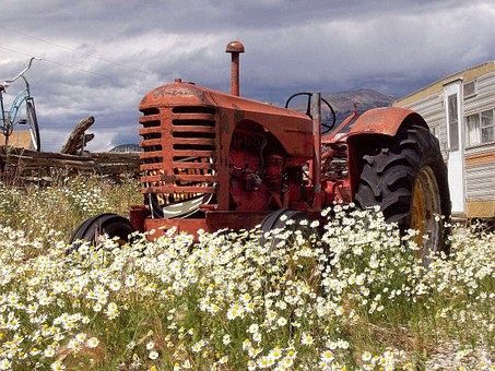 A tractor sits in a field near a pole barn.