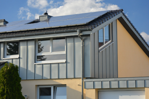 A 3/4 view of a home with sheet metal siding on some parts of it. There are blue skies in the background 