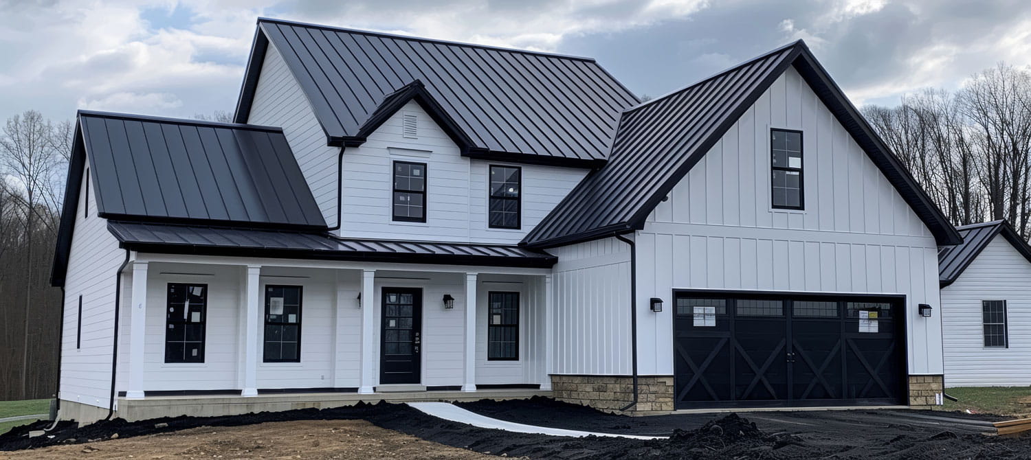 Black metal roofing across every gable and porch of a newly built white farmhouse, with black windows and X-braced garage doors.